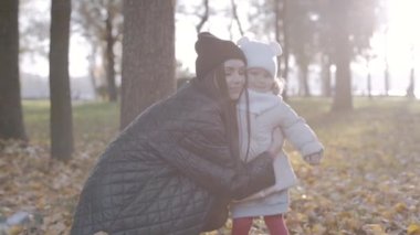 Mutlu aile, anne ve kızı sonbaharda parkta birlikte. Yavaş çekim
