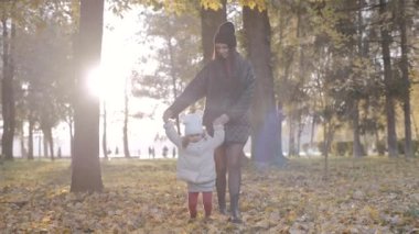 Mutlu aile, anne ve kızı sonbaharda parkta birlikte. Yavaş çekim