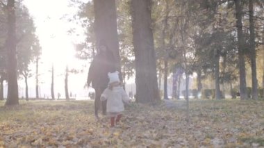 Mutlu aile, anne ve kızı sonbaharda parkta birlikte. Yavaş çekim