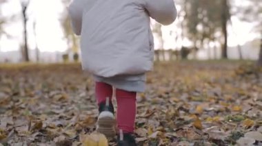 Sonbahar parkında koşan çocuk güneşli bir günde, ağır çekimde