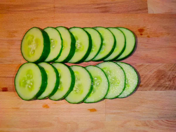 Tahta kesme tahtasında dilimlenmiş salatalık.