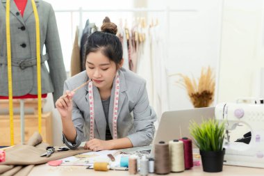 Evden çalışıyorum. Galeride Asyalı genç kadın moda tasarımcısı tasarımı üzerinde çalışıyor. Yaşam tarzı insanlar, stüdyoda mankenlerin ölçülerini alan terziler gibidir. İş küçük Kavram