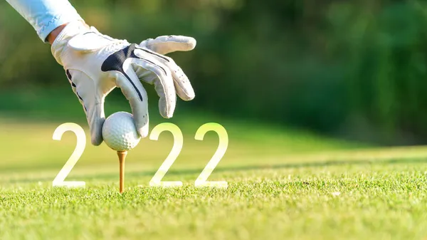 Kapalı el golfçüsü kadın yeni sağlığına kavuşması için yeşil golfe Mutlu Yıllar 2022 için golf topu koyuyor. kopyalama alanı. Sağlıklı ve Tatil Konsepti.