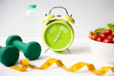 2021 ve 2022 'de alarm saati ve diyet için egzersiz planlaması. Spor aletleri egzersizi ve spor için taze salata. Mutlu Noeller ve mutlu yıllar konsepti