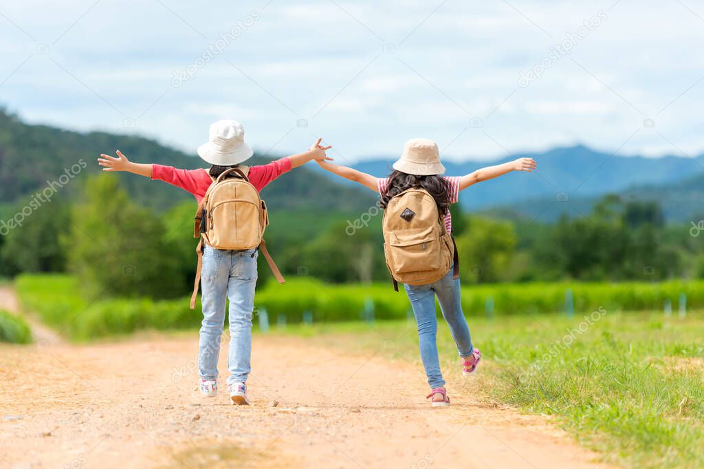 Asian girl raise arms and jumping on the green meadow outdoors adventure. People kid tourism traveling education nature forest for destination and leisure trips with mountain.  Travel vacations