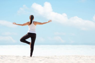Yaşam tarzı atletik kadın yoga egzersizi ve sağlıklı yaşam için poz vermek. Genç kız ya da insanlar dengeli vücut pozu veriyor. Zen ve meditasyon egzersizi ve açık kumsalda spor sporu. Deniz ve gökyüzü arkaplanı