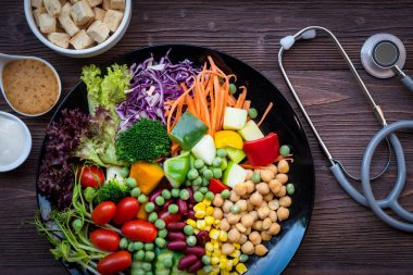 Sağlık Hizmetleri. Diyet için tıbbi steteskoplu taze sebze salatası ve sağlıklı bakım ve virüsü korumak için kilo kaybı, eski ahşap arka plan. Sağlıklı Yaşam Konsepti