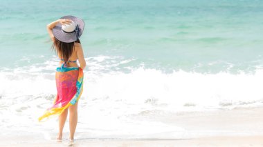 Yaz tatili. Yaşam tarzı kadın soğuk büyük beyaz şapka tutarak ve bikini moda yaz gezileri kumlu okyanus plajda yürüyüş giyiyor. Mutlu kadın keyfini çıkarın ve tatil dinlenmek. Yaşam Tarzı ve Seyahat Konsepti