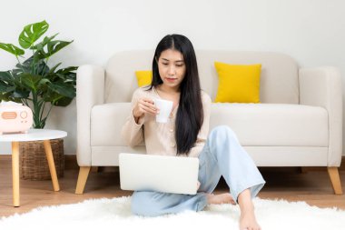 Mutlu genç bir kadın işten sonra sıcak portakallı kahve içiyor ve evde buluşuyor. Yaşam tarzı serbest çalışma. Oturma odasında rahatla ve rahatla. Yaşam Tarzı Konsepti