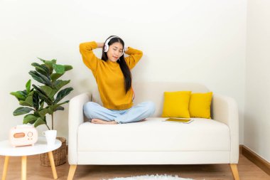 Gülümseyen genç kadın, yaz tatilinde rahatlamak ve rahatlamak için müzik dinlemekten mutlu olur. Yaşam tarzı kızı evdeki oturma odasında dizüstü bilgisayar kullanarak eğleniyor. Yaşam Tarzı Konsepti 