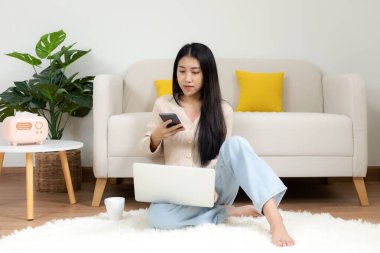 Mutlu genç bir kadın evde online alışveriş yapmak için akıllı telefon kullanıyor. Yaşam tarzı rahatlamak ve oturma odasında kahve içmek. Yaşam Tarzı Konsepti