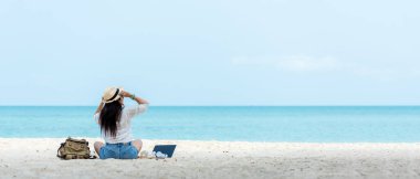 Hayat tarzı bağımsız bir kadın dizüstü bilgisayar kullandıktan sonra müzik dinler ve plajda dinlenir. Asyalıların başarısı ve birlikte iş meşgaleniz ve tatilde internette konferansınız.