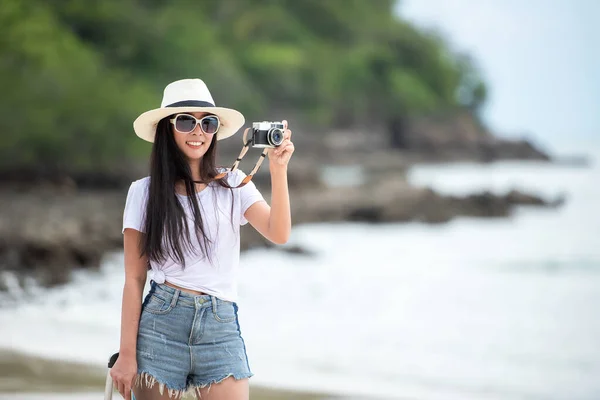 Happy traveler and tourism young women travel summer on the beach. Asian  people holding map and camera take photo  and relax outdoor for destination and leisure trip travel in holiday