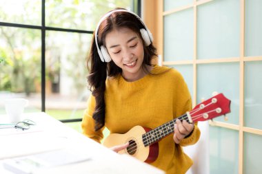 Young woman happy listen music for chill and relax after finish work.   Lifestyle girl using laptop for meeting and working  in living room at home.  Lifestyle Concept 
