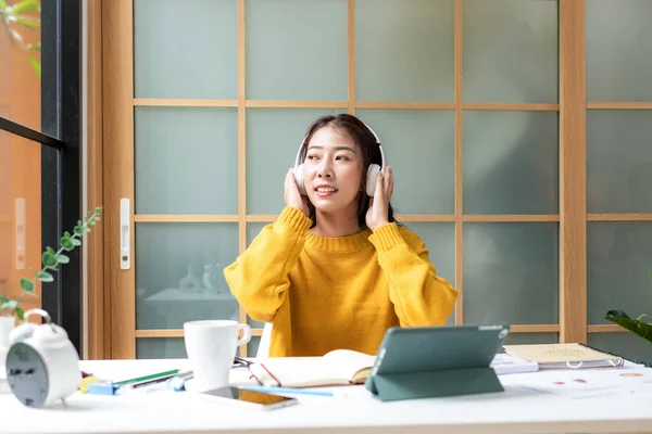 Young woman happy listen music for chill and relax after finish work.   Lifestyle girl using laptop for meeting and working  in living room at home.  Lifestyle Concept