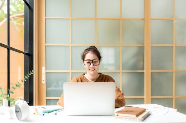 Gençler evde dizüstü bilgisayarla çalışır ve sabahları kahve içerler. Evde dinlenirler. Asyalı kadın toplantı konferansı ofisi internet üzerinden bağlıyor. İş ve Teknoloji Konsepti