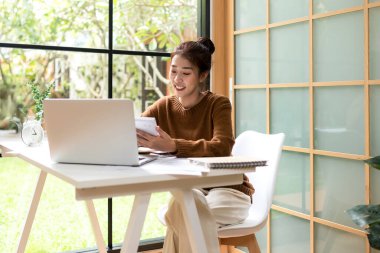 Gençler evde dizüstü bilgisayarla çalışır ve sabahları kahve içerler. Evde dinlenirler. Asyalı kadın toplantı konferansı ofisi internet üzerinden bağlıyor. İş ve Teknoloji Konsepti