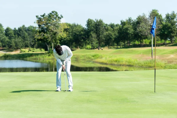 Golfer sport course golf ball fairway. People lifestyle man  putting golf ball on the green grass. Asian man player game shot in summer