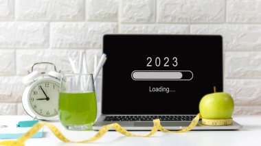 Yeni bir işe başlamak ve yeni bir hayata başlamak için 2023 yılı yükleniyor. Ofiste çalışırken sağlıklı atıştırmalıklar ve ekipman sporu. Diyet için yeşil elma ve taze su Sağlık Planlama