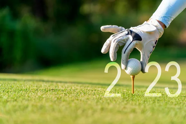 Kapalı el golfçüsü kadın yeni sağlığına kavuşması için yeşil golfe Mutlu Yıllar 2023 için golf topu koyuyor. kopyalama alanı. Sağlıklı ve Tatil Konsepti
