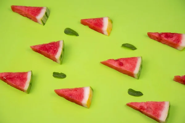 watermelon slices with fresh mint leaves on a pastel green backg