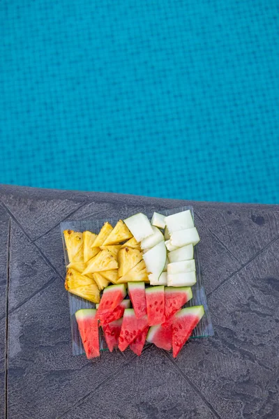 fresh fruit platter on the stamped concrete by the pool, healthy diet