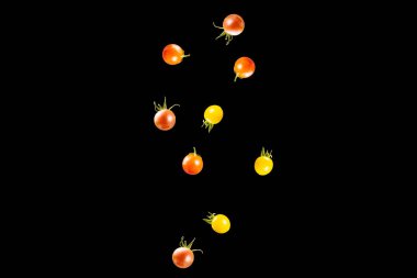cherry tomatoes of different varieties falling on a black background