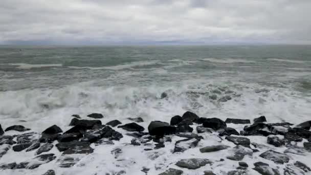風と嵐の天候で岩に衝突する波によって形成された白い泡 — ストック動画