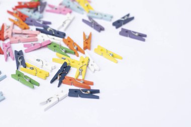 Beyaz arka planda bir sürü renkli mini mandallar, renkli ahşap mandallar.