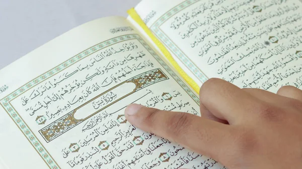 Asia, India, Pakistan. an open page of the Quran shows Surah Yaseen pointing with her finger on white background. Quran is an Islamic holy book for Muslims. and Ramadan is the month of the Quran..