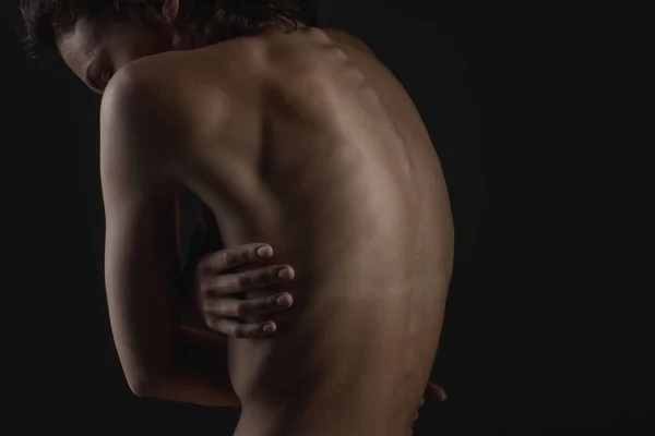 girl's back close-up on a dark background, the concept of treatment of the spine and back