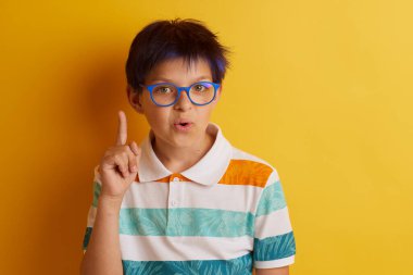 Sarı arka planda farklı duyguları olan gözlüklü bir çocuk, mesaj için boş yeri olan bir karton afiş tutuyor.