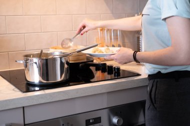 Evdeki mutfakta makarna yapan tanınmayan bir kadın.