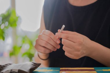 Tanınmayan biri evde sigara yapıyor.