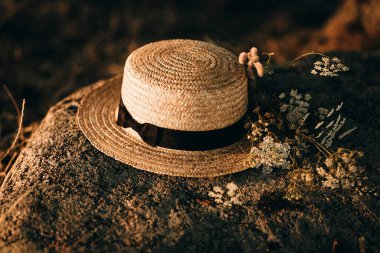 Beyaz çiçekli bir taşın üzerinde hasır şapka