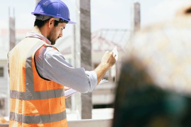 Zeki inşaat mühendisi bina inşaatında çalışıyor ve bina planlarını inceliyor. mühendislik ve mimari kavramı.