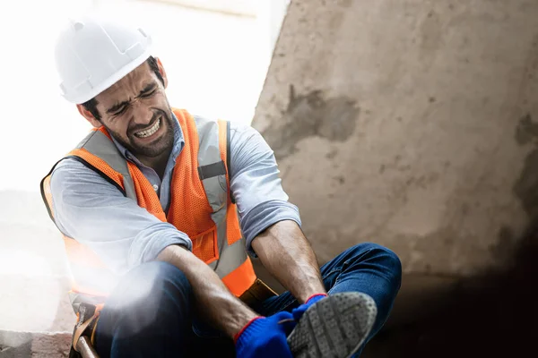 Handsome engineer injured his ankle when he stepped on a nail while inspecting a house project. Concept of occupational safety and occupational accident insurance.