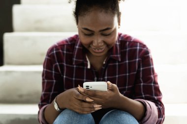 Akıllı telefondan bilgi okuyan güzel kıvırcık kadın.