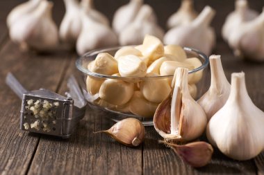 Arka plandaki ahşap kırsal masada organik sarımsak soğanları soyulmamış bir yığın sarımsak.