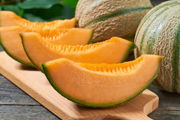japanese melon, honey melon or cantaloupe melon on a cutting board and rustic wooden table.