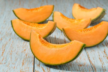 Mavi ahşap bir masada dilimlenmiş Japon kavunu.