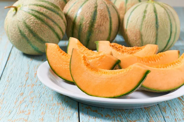 Sliced japanese melon, honey melon or cantaloupe melon in a ceramic plate on a wooden table.