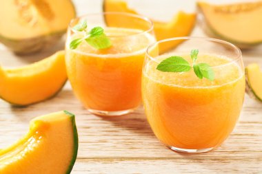 İki bardak kavun püresi taze kavun ve ahşap bir masada nane şekeri..