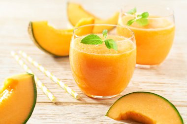 Ahşap masadaki bardaklarda kavun suyu ya da taze kavun içeceği. Sağlıklı beslenme kavramı.