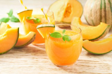 Bardaklar dolusu lezzetli meyve püresi taze kavun ve ahşap bir masada nane şekeri..