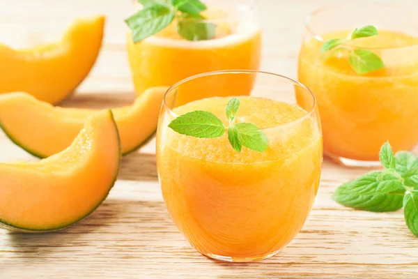 Bardaklar dolusu lezzetli meyve püresi taze kavun ve ahşap bir masada nane şekeri..