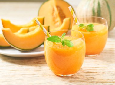 Bardaklar dolusu lezzetli meyve püresi taze kavun ve ahşap bir masada nane şekeri..