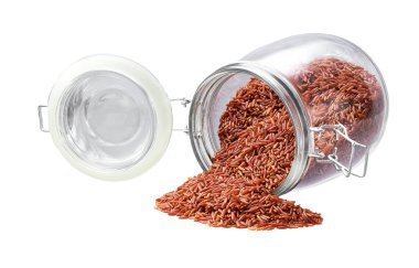 Beyaz arka planda izole edilmiş cam bir kavanozdan organik kırmızı pirinç döküldü..