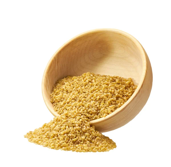 Organik kuru bulgurlar beyaz arka planda izole edilmiş ahşap kaseden dışarı saçılmış..