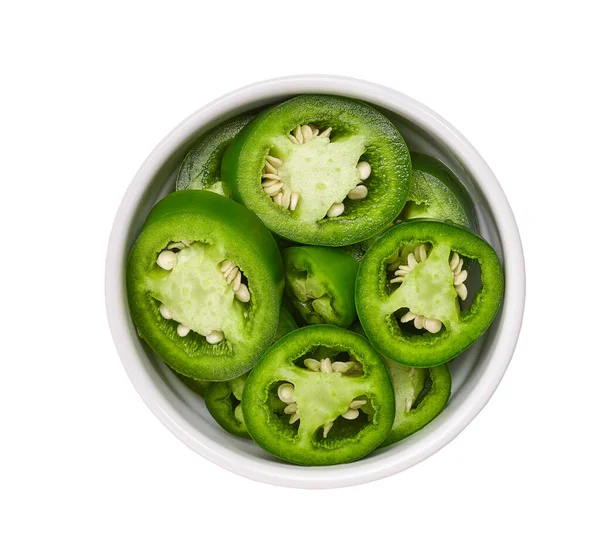 Organic green cut chili pepper pieces in a white ceramic bowl isolated on white background top view.